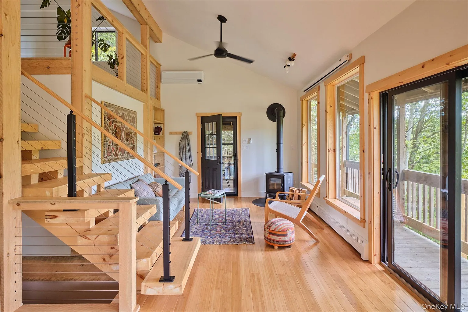 Entry room with a wood stove, bright windows and open wooden staircase