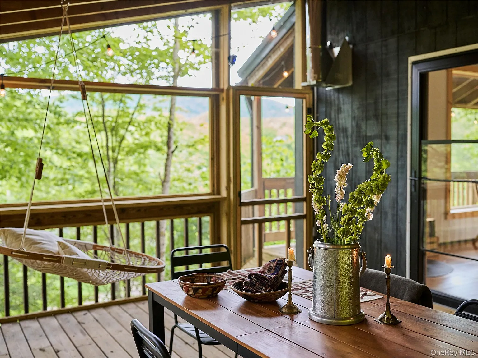 Screened porch with a hanging hammock chair and a wooden dining table