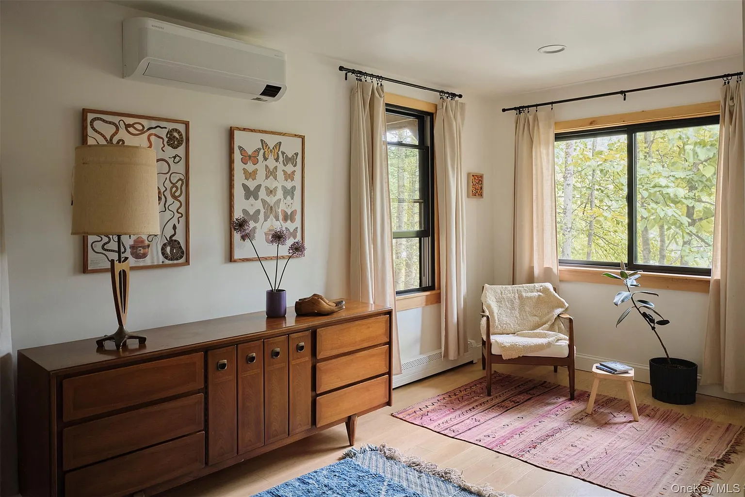 Bright room with a vintage wooden dresser and armchair beside big windows